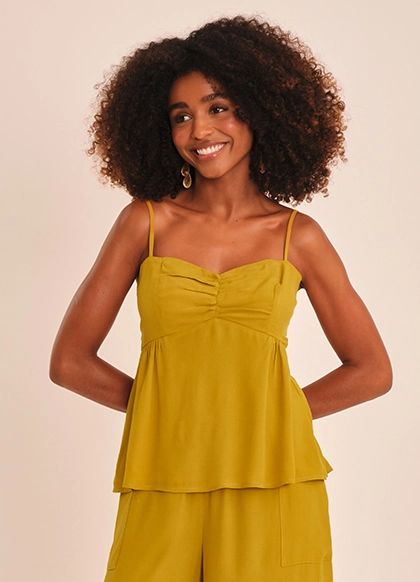 Modelo sorrindo de blusa mostarda
