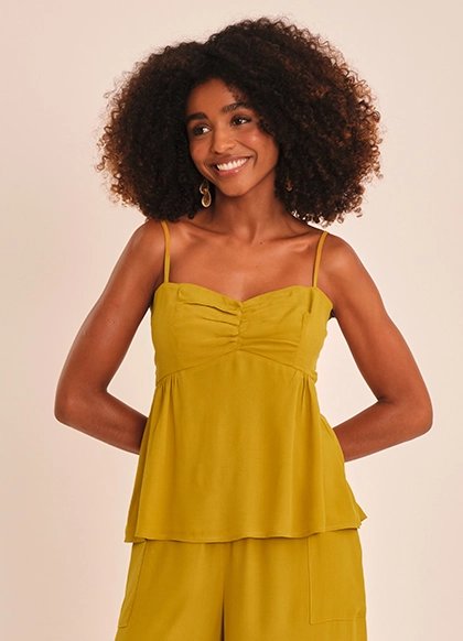 Modelo sorrindo de blusa mostarda